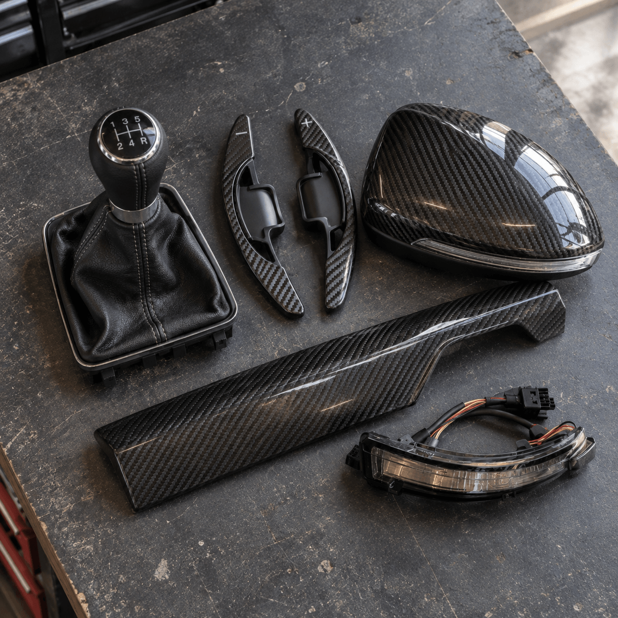 Accessoires tuning réunis sur un établi : pommeau, palettes, coque et garniture carbone
