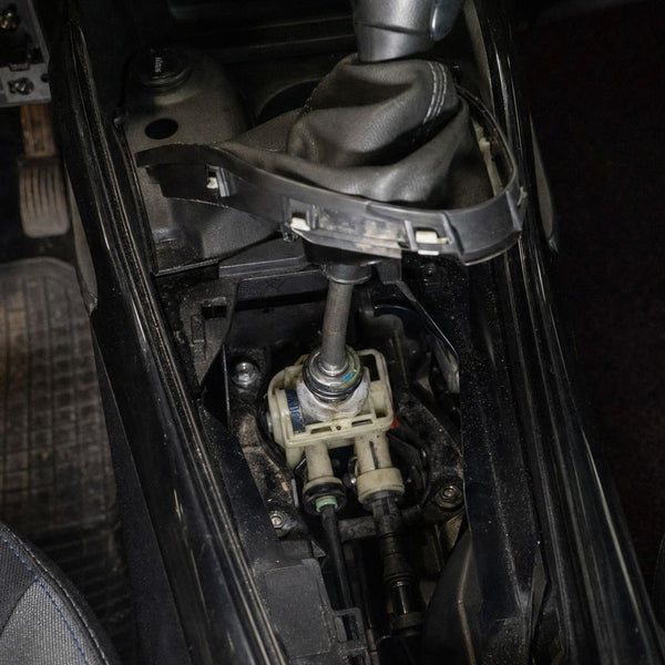 Commande de boîte d'une Peugeot 208 sous le soufflet relevé : base du levier et départ des câbles de tringlerie