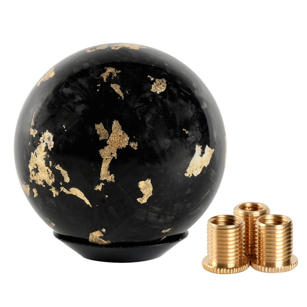 Pommeau de vitesse tuning de forme ronde en fibre forgée, de couleur noir et or.