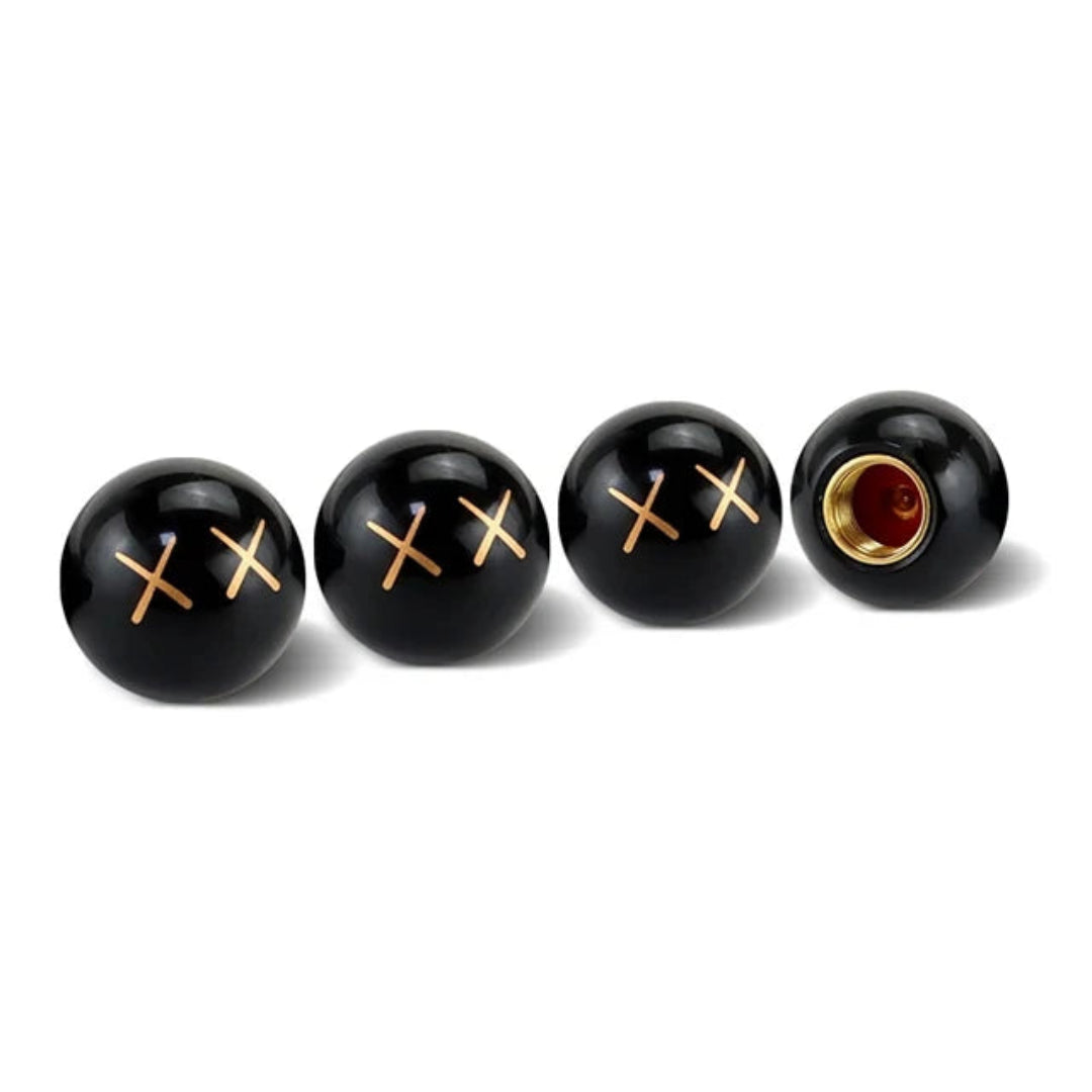 Bouchon de valve noir, avec des croix doré sur le bouchon.