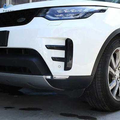 Cache grille pare-chocs noir brillant posé sur l'entrée d'air latérale d'un Land Rover blanc