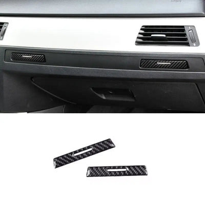Deux caches carbone posés sur les poignées de porte-gobelets passager d'une BMW E90