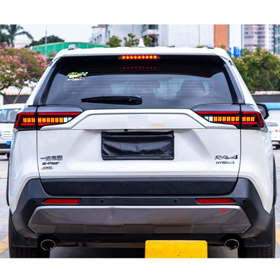 Toyota RAV4 hybride blanc vu de l'arrière avec les feux LED allumés