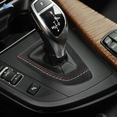 Garniture levier de vitesse BMW en suédine à double surpiqûre bleu clair et rouge, posée autour du sélecteur automatique