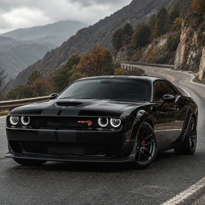 Dodge Challenger noir équipé des phares LED, anneaux allumés sur route de montagne