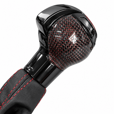 Gros plan sur le pommeau Audi Q2 noir brillant à motif carbone tramé de rouge