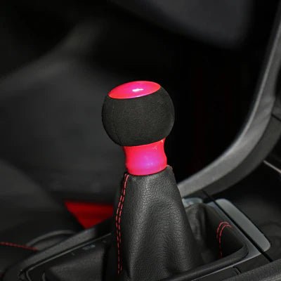 Pommeau de vitesse rose monté sur le levier, sphère en suédine noire et embase rose fluo